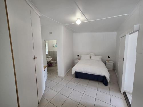 ein weißes Schlafzimmer mit einem Bett und einem Badezimmer in der Unterkunft The Genet Cottage in Reebok