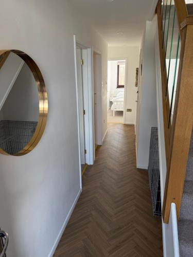 a hallway with a round mirror on a wall at Sienna Cottage in Benllech