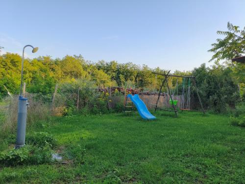 a yard with a playground with a blue slide at Kamilla Vendégház in Ács