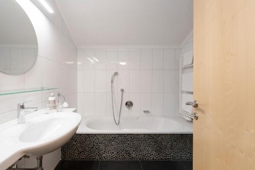 a white bathroom with a tub and a sink at Hotel Stubaierhof in Neustift im Stubaital