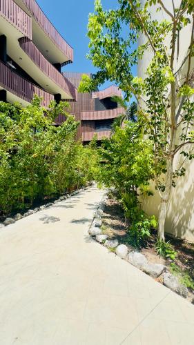 a walkway in front of a building with trees at Jungle Guardian - Rooftop Pool & Beach Club in Zona Hotelera Tulum in Tulum