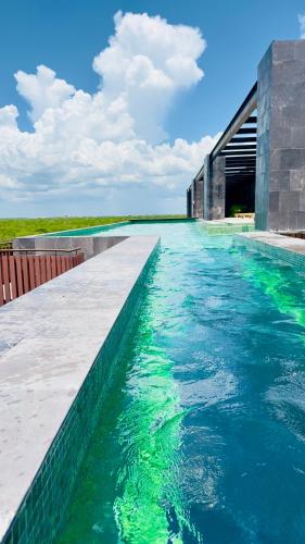 a swimming pool with green water in front of a building at Jungle Guardian - Rooftop Pool & Beach Club in Zona Hotelera Tulum in Tulum