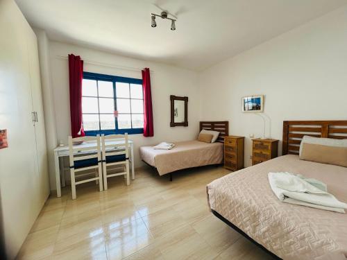 ein Schlafzimmer mit zwei Betten und einem Schreibtisch und einem Fenster in der Unterkunft VILLA BARRACUDA - "Seaview 3min walk to the beach" in Playa Blanca