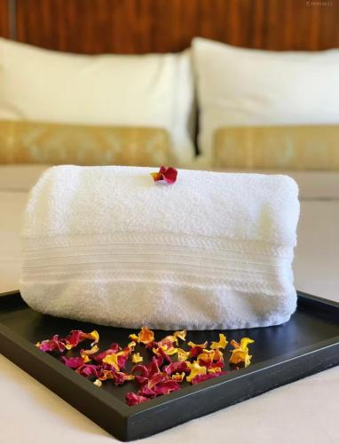 a white towel on a tray with flowers on a bed at Love Home Inn in Richmond
