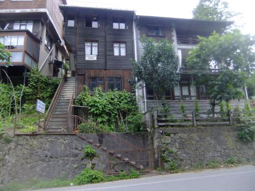 an old wooden house with stairs on a stone wall at KONAKLAR APART in Çamlıhemşin