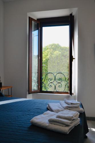 a bedroom with a large window with towels on a bed at Casa di Aurora in Guidonia