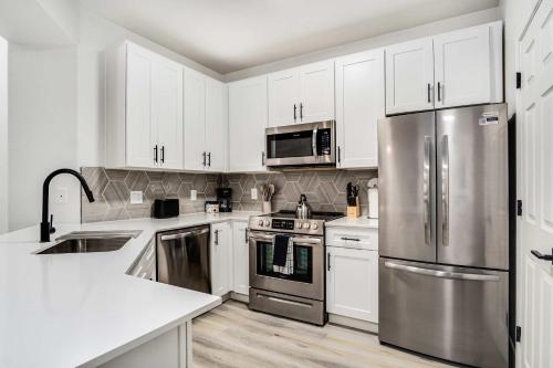 a kitchen with white cabinets and stainless steel appliances at Boulevard Stays 2BR by Stadium Pool Parking Gym 05 in Glendale