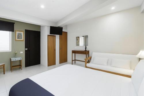 a bedroom with a white bed and a couch at Casa Santa Fe in Guanajuato