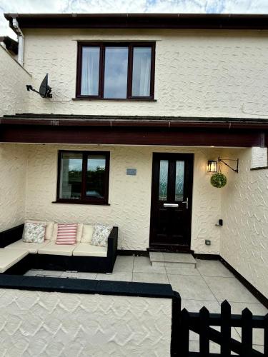 a white house with a couch in front of it at Sienna Cottage in Benllech