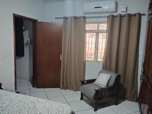 a bedroom with a chair and a window at Pousada Cantinho do Sossego in Várzea Grande