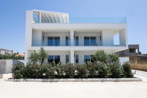 a white house with flowers in front of it at Dara Holiday Apartments in Marsala