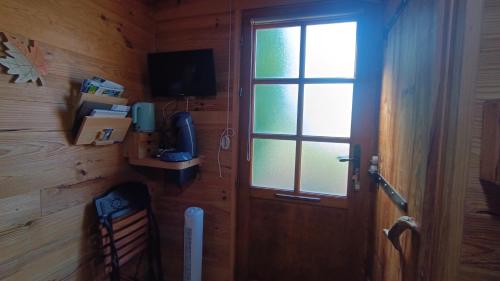 una habitación con una puerta con una ventana y un televisor en patrice et chrstel Cabane en bois, en Chatuzange-le-Goubet