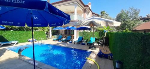 a swimming pool with blue chairs and umbrellas at Villa Balım in Koycegiz