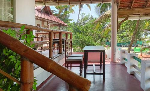 a porch of a house with a table and chairs at Marari Praise Beachfront Homestay in Mararikulam