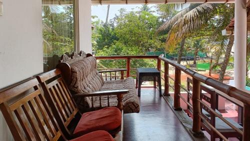a porch with chairs and a balcony with a view at Marari Praise Beachfront Homestay in Mararikulam