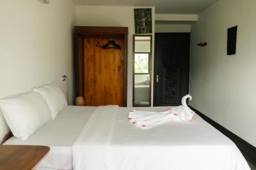 a bedroom with a white bed with a towel on it at Pomelo Outpost Cambodia ដំណាក់ភ្នំក្រោម in Phumĭ Rœssei Lŭk