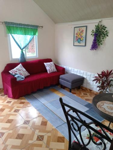 a living room with a red couch and a table at La Cabañita in Alto Boquete