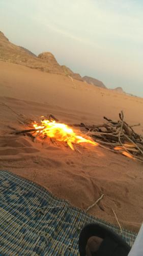 a fire in the sand in the desert at Wadi rum shadi camp in Wadi Rum