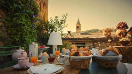 une table avec des paniers de pain et une vue sur une église dans l'établissement Les chambres d'Elise, à Collias