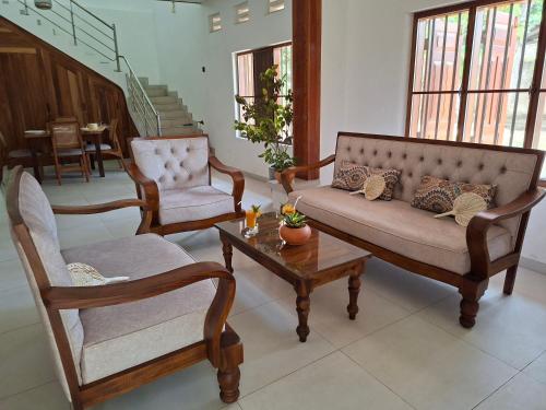 a living room with two chairs and a couch and a table at Naolina Beach Villa in Weligama