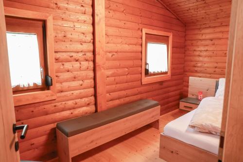a bedroom in a log cabin with a bed and two windows at Landhausidylle in Sankt Gilgen
