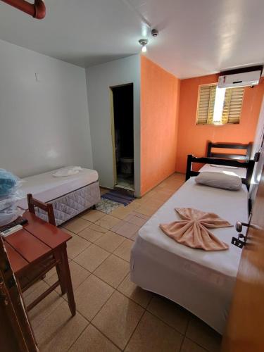 a room with two beds and a table and a room with a room at Hotel Jardim Goiás in Rio Verde