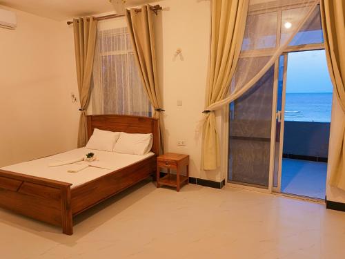 a bedroom with a bed with a view of the ocean at 2BR Beachfront Apartment with Balcony & Sea Views - Uroa, Zanzibar in Uroa