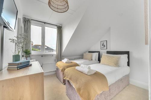 two beds in a white room with a window at Palm House in Newquay
