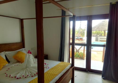 a bedroom with a canopy bed and a sliding glass door at Ocean Bliss Beach Resort in Pongwe