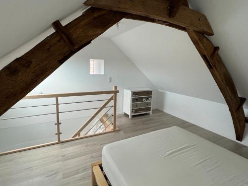 a attic room with a bed and a staircase at La Basse Meule Maison in Juvigné