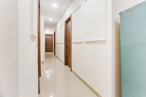 a hallway in a house with white walls and wooden doors at Super Hotel O A K Residency in New Delhi