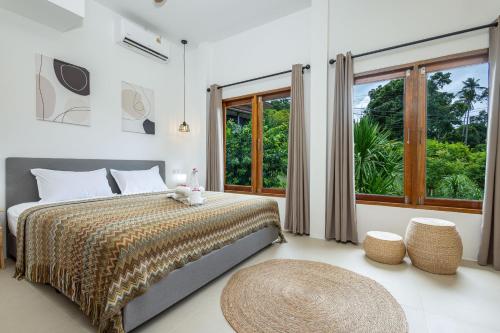 a bedroom with a bed and a large window at BOHO Boutique Bungalows in Baan Tai