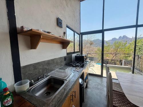 a kitchen with a sink and a counter with windows at Piedra Cobre Panoramic in Tepoztlán