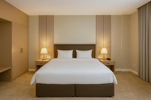a bedroom with a large white bed and two lamps at Towlan Alrayan in Quai