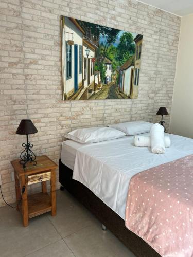 Un dormitorio con una cama y un cuadro en la pared. en Pouso do parente, en Pirenópolis
