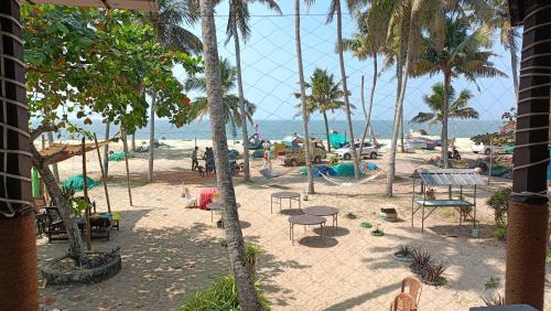 a view of a beach with palm trees and chairs at Marari Praise Beachfront Homestay in Mararikulam