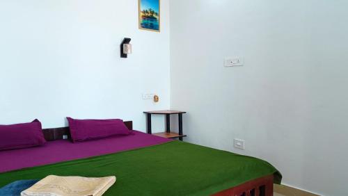 a bedroom with a bed with purple and green sheets at Marari Praise Beachfront Homestay in Mararikulam