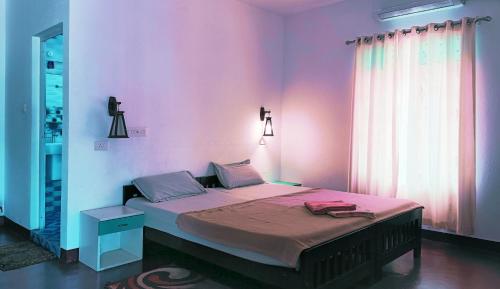 a bedroom with a bed with pink walls and a window at Marari Praise Beachfront Homestay in Mararikulam
