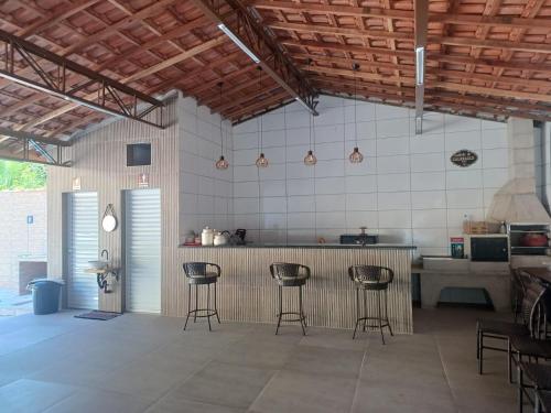 a kitchen with three bar stools in a room at Recanto Julebi in Guaratinguetá