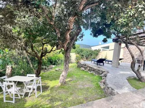 a picnic table and bench in a yard with trees at Charming Sardinian Dream Home in Marazzino