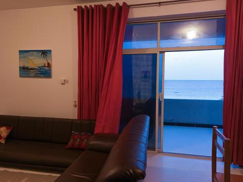 a living room with a couch and a view of the ocean at 2BR Beachfront Apartment with Balcony & Sea Views - Uroa, Zanzibar in Uroa