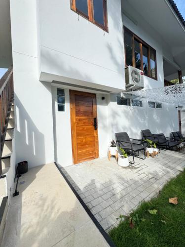 a white house with a wooden door and a patio at BOHO Boutique Bungalows in Baan Tai