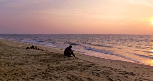 a group of people sitting on the beach at sunset at Marari Praise Beachfront Homestay in Mararikulam