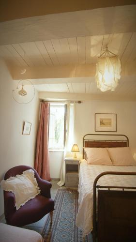a bedroom with a bed and a chair and a window at Les chambres d'Elise in Collias