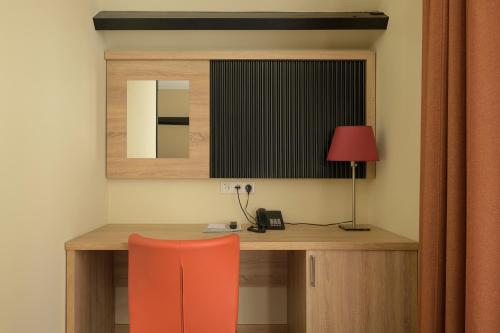 a desk with a red chair and a lamp at Atlas Village Brielle in Brielle