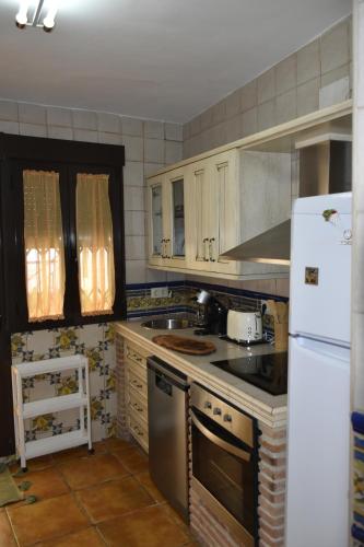 a kitchen with white cabinets and a white refrigerator at Casa rural El Carmen in Baños de la Encina