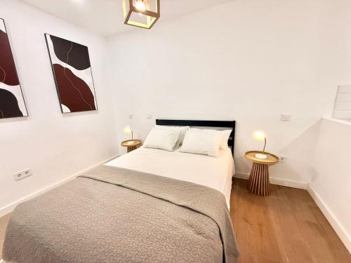 a white bedroom with a bed and two tables at Renfe Asamblea de Madrid 03 AMCH Hospedaje in Madrid