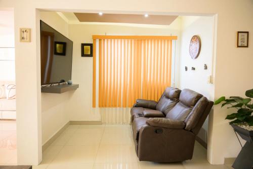 a living room with a brown leather chair and a television at Casa Teresita - Amplia y cómoda en zona tranquila y bien conectada in Aguascalientes