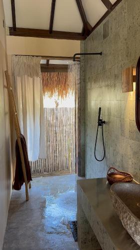 a bathroom with a sink and a window with a shower at NIRA Surf Villas in Maluk