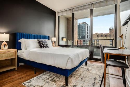 a bedroom with a blue bed and a desk and window at Boulevard Stays 5 mins to Riverwalk & Mag Mile 03 in Chicago